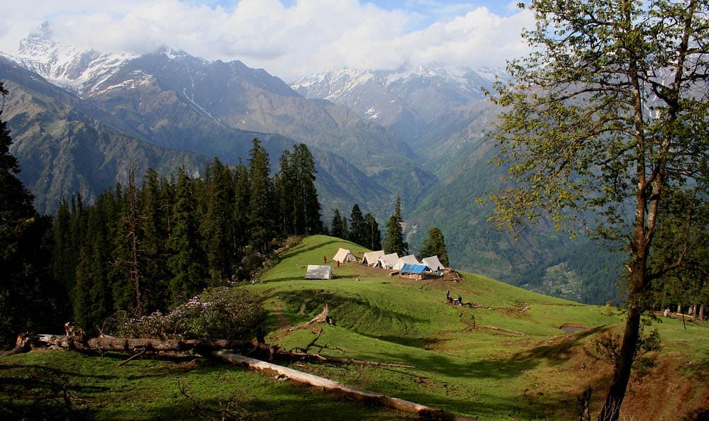 Tents on the Biskeri meadow below wooded mountain slopes